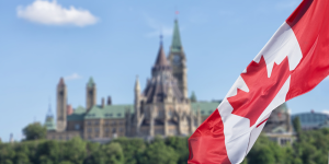 Canadian flag with parliamentary building in the background